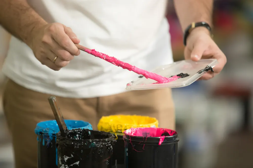 Hände mischen Druckfarben in Cyan, Magenta und Gelb
