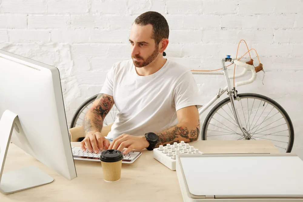 Mann im weißen T-Shirt gestaltet am Computer ein Motiv